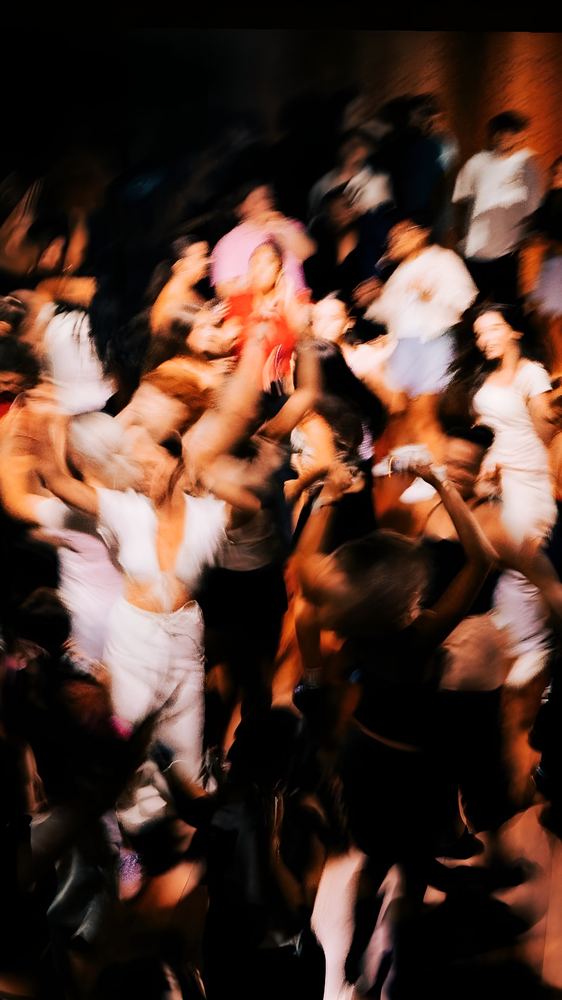 A crowd dancing, blurred, under warm light